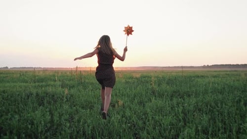 Girl Child Running with a Windmill in a Field