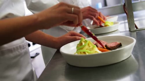 Close-up of team of chefs garnishing dishes
