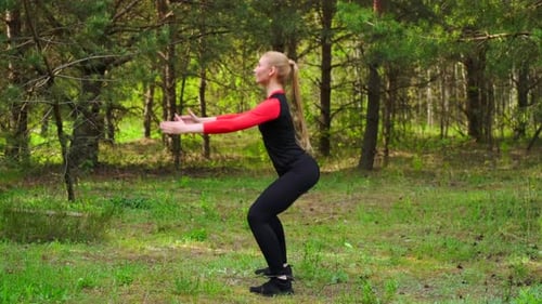 View In Profile Of Sportive Girl Doing Squats In Park