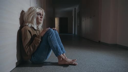 Distressed Woman Sitting on Floor in Dark Hallway