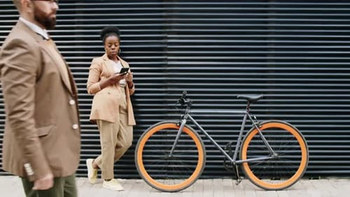 Afro-American Woman Using Smartphone by Bike on Street