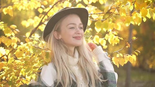 Portrait of Caucasian Blonde Woman in Hat Posing Near Forest Tress
