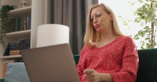 Woman With Glasses Talks on Laptop at Home