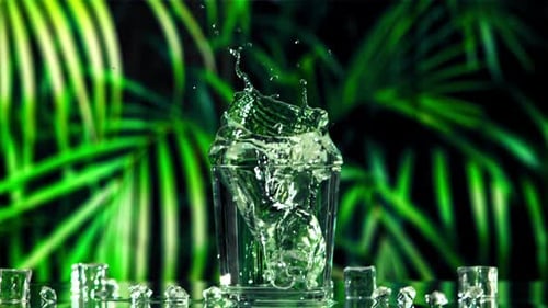 An Ice Cube with Splashes Falls Into a Glass of Water