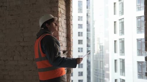 Design Engineer at a Construction Site Looking at the Construction Drawings