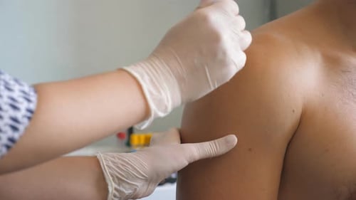 Nurse in Gloves Making a Vaccine Injection to Hand of Male Patient in Health Clinic