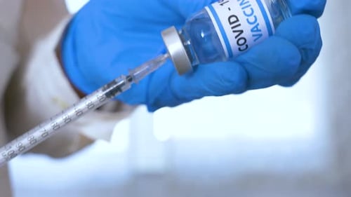 Doctor hands with blue surgical gloves holding syringe and COVID-19 vaccine. COVID-19 vaccine.