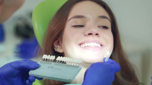 Doctor Examining Patient Teeth Whiteness. Close Up Dentist Selecting Color