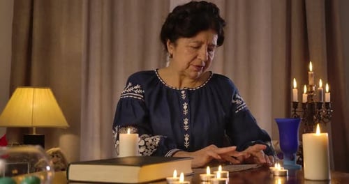 Woman Reads Cards in Candlelit Room