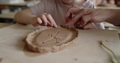 Grandmother Teaches Her Granddaughter to Mold Clay in Pottery Workshop