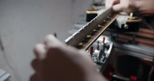 Luthier ajuste l'angle du manche de la guitare électrique montée sur le gabarit pour réparer la comédie musicale