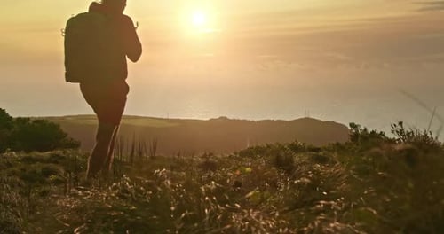 Tourist with a Backpack Climbs Onto a Hill During Sunset