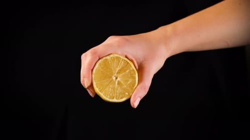 Mujer exprimiendo jugo de limón sobre fondo negro