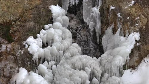 Icy Waterfall Cascading Down Rock Face in Winter