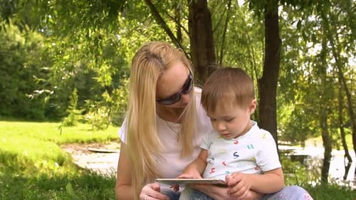 Mother and Child Using Tablet in Green Park