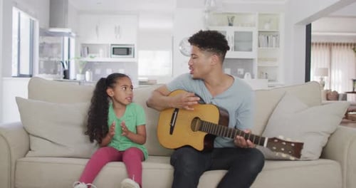 Man Plays Guitar with Little Girl in Living Room