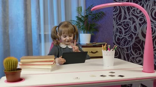 Girl Waves and Smiles Using Tablet Indoors