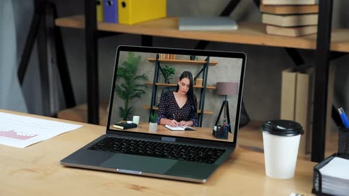 Laptop Standing on Table Display with Businesswoman in Office Writes in Notebook