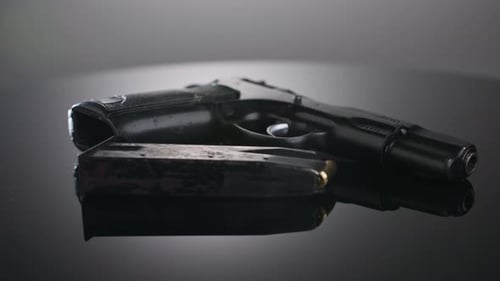 Waffenkontrolle. Studioaufnahme einer 9-mm-Pistole, die sich auf einer reflektierenden Oberfläche dreht