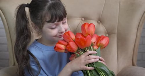 Young Girl Smells Bouquet of Red Tulips
