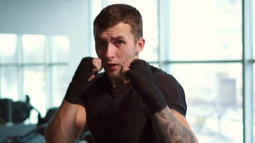Man Boxing and Punching in Bright Gym