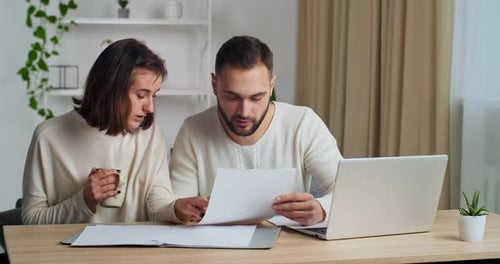Couple Reviewing Documents Together at Home Desk
