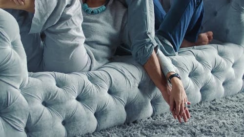 Couple Relaxing Comfortably on Couch Holding Hands