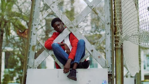 Pensive man sitting on a metal structure