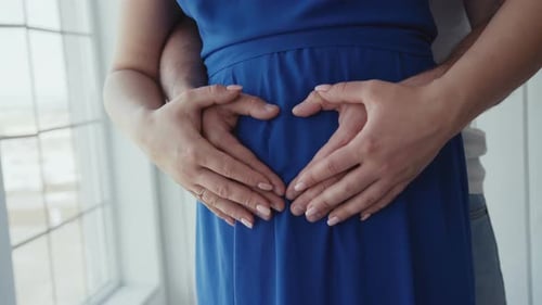 Vue rapprochée des mains masculines et féminines touchant et caressant l'utérus dans le ventre