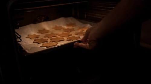 la niña pone en el horno una bandeja para hornear con galletas y pan de jengibre para cocinar