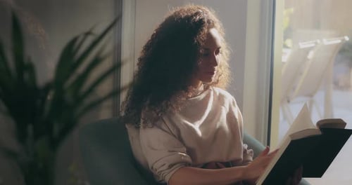 Girl with curly hair reading a book