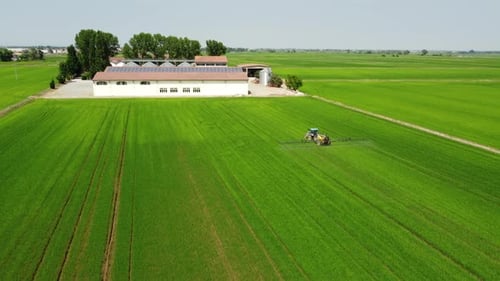 Tractor and Farmer Spraying Fertilizer, Herbicide, Pesticide on Agriculture Farm Field