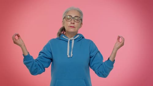 Senior Woman Meditating Against a Pink Background