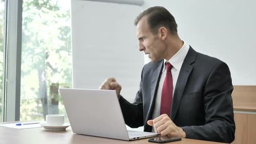 Frustrated Businessman Typing at Desk in Office