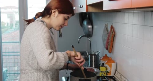 Young Woman Cooking Food in a Pot Indoors