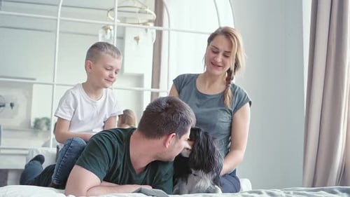 Loving Family Relaxing Together on Bed With Dog