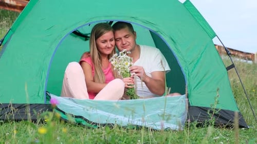 Couple With Flowers Cuddling Inside Camping Tent
