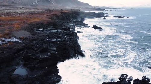 Aerial Top View of Waves Break on Rocks in a Blue Ocean