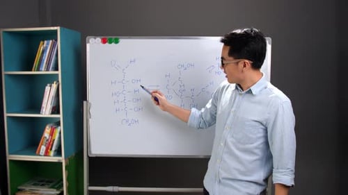 Adult Explaining Chemical Structures on Whiteboard