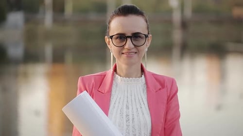 Woman smiling holding papers wearing pink blazer