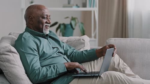 Senior Man Using Laptop Computer While Relaxing on Couch
