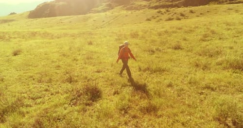 Flight Over Backpack Hiking Tourist Walking Across Green Mountain Field