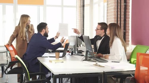 Group of Young Colleagues Discusses a New Project Sitting in the Interior of a Modern Office