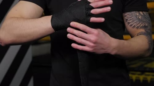 Man Wrapping Hands in Black Boxing Wraps