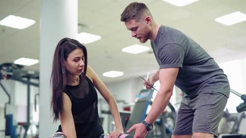 Young and beautiful woman working out with dumbbells in gym. Personal fitness instructor.
