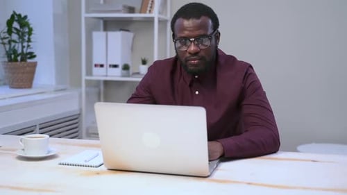 Man Working on Laptop and Taking Notes at Desk