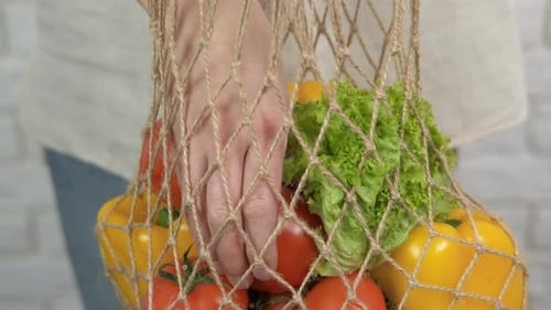 Taking Tomato From Reusable Vegetable Shopping Bag