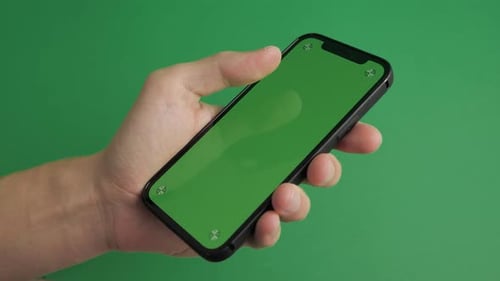 Closeup of Male Hand Holding Mobile Telephone with Vertical Green Screen Chroma Key Smartphone