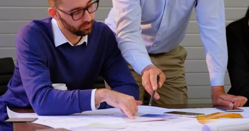 Executives discussing over blueprint in conference room at office