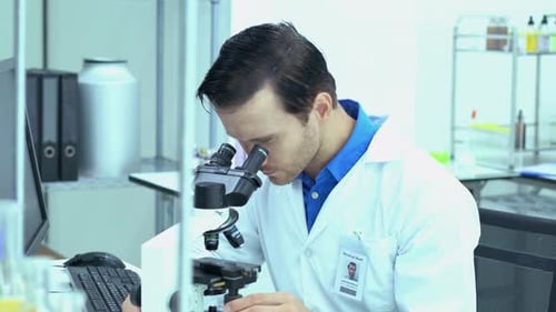 Focused Scientist Using Microscope in Modern Laboratory